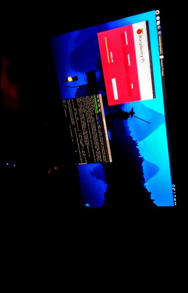 The photograph composed in total darkness, shows a computer monitor displaying a desktop environment with a blue-themed wallpaper featuring a silhouette of a samurai holding a sword against a mountainous background. The screen is tilted at an angle, with the top right corner showing a red window with the text "Raspberry Pi" and a logo, indicating the operating system. Below this window, there is a terminal window with white text on a black background, displaying lines of code or commands. The bottom left corner of the screen shows a black terminal window with white text, possibly displaying system information or logs. The monitor is in a dark room, with only the screen providing illumination. The bottom right corner of the screen shows the time as "10:01" and some system icons.

Provided by @altbot, generated privately and locally using Ovis2-8B

🌱 Energy used: 0.182 Wh