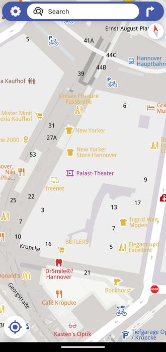 Screenshot of the app Magic Earth: The map of a shopping district in Hanover, Germany, highlights various stores, cafés, and landmarks. In the centre of the map, the Palast-Theater is labeled in purple, surrounded by shops like New Yorker and BUTLERS. Nearby streets and points of interest are also shown.