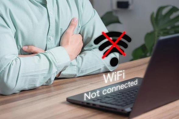 Man using a laptop, No wifi symbol and text "WiFi Not Connected" overlaying it.