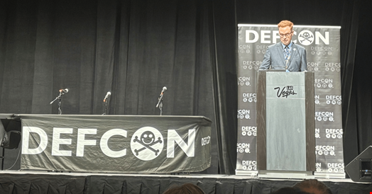 Jim O'Neill, Deputy Secretary, HHS on stage with a DEFXON banner