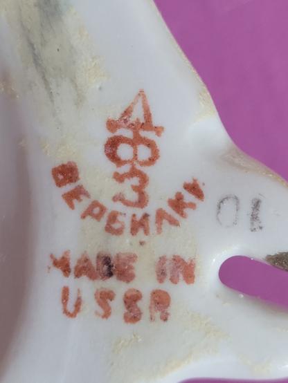 Stempel auf der Unterseite einer Porzellanfigur.
Es zeigt eine Symbolreihenfolge (von oben nach unten): Dreieck, liegende Acht (oder so ähnlich), die Zahl Drei
Darunter stehen die Buchstaben BEPSKAKV (oder ähnlich)
Und darunter Made in USSR