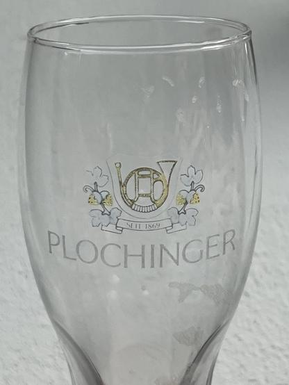 Ein altes Weizenbierglas, auf dem noch Reste der Goldprägung zu erkennen sind: Ein Waldhorn und darunter der Schriftzug „Plochinger“