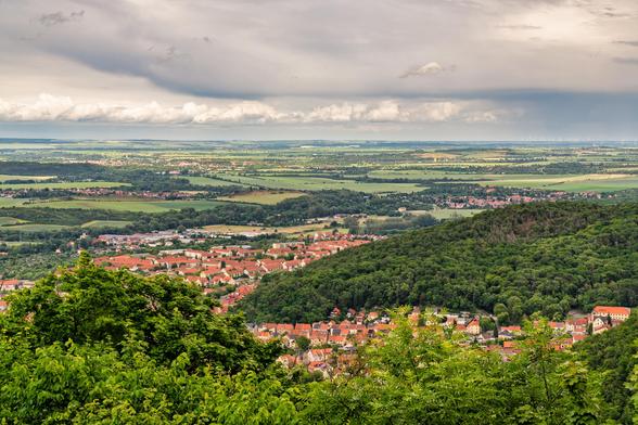 Blick auf die Stadt Thale rote Dächer getrennt durch Berge und dahinter Blick auf die flache Landschaft.
