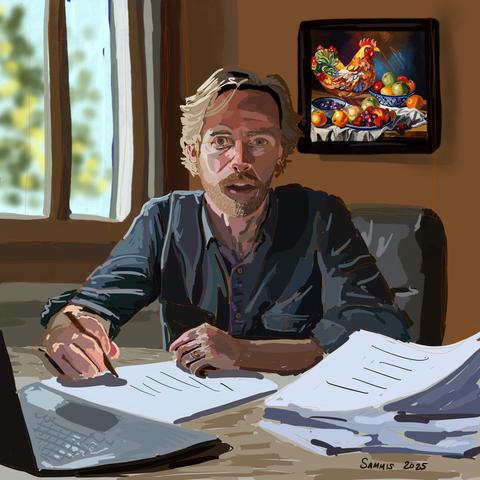 Eric, just shy of 50 years old now, is mid conversation with Susan (not shown) as he suggests a way out of an impossible situation they've been put in. He's sitting at a desk covered in papers and an open lap top.
