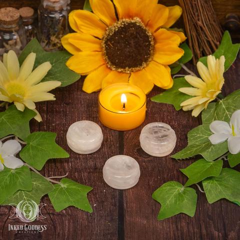 Three specimens of the "Clear Quartz Sphere Holder" product are arranged on a wooden surface. They are polished and carved into a small cup-like shape. Their color ranges from transparent to opaque white. Presented by Inked Goddess Creations.