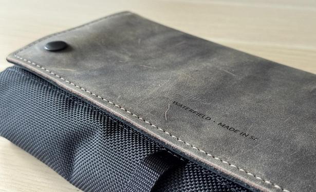 Detailaufnahme eines Waterfield CitySlicker Cases für die Nintendo Switch 2 mit brauner Lederklappe und schwarzem Nylonmaterial. Auf dem Leder ist mittig in kleiner Schriftart in Großbuchstaben „Waterfield - Made in SF“ eingeprägt.