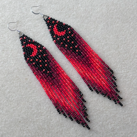 A pair of red and black beaded fringe earrings with crescent moon and stars on the top