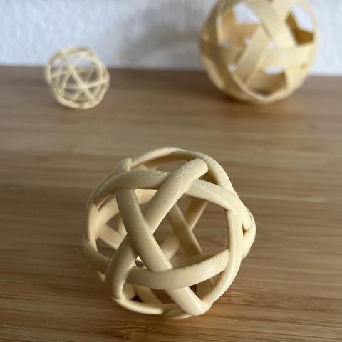 photo of 3d printed ribbon balls laying on the desk in different sizes and different ribbons, closeup