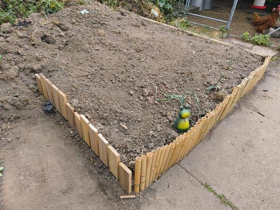 A raised earth bed with wooden and bamboo edging that prevents the loose earth from settling onto the path
