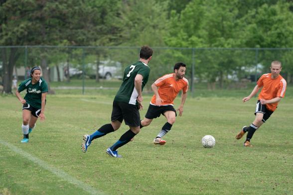 A Hokie player cuts in from the sideline with the ball, as a teammate runs alongside and two opponents defend.
