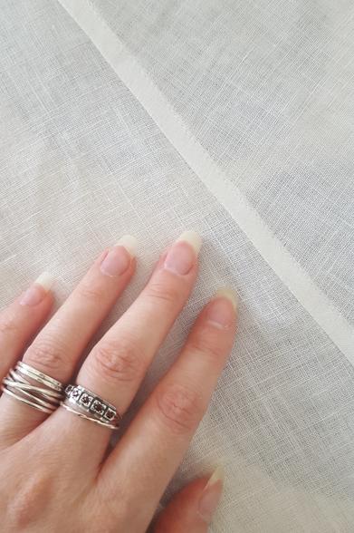 A flat felled seam, with Sini's pink hand for scale. It has a touch of machine precision about it, the seam. Despite going on the bias on linen which is notoriously wibbly, it's very exactly top stitched, flat and nice. It's also quite narrow, only 9mm wide, and looks pretty lovely and neat in the crisp white fabric.