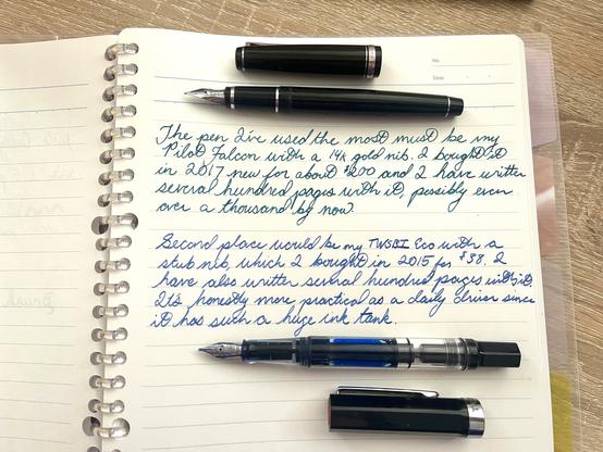 Handwritten page upon which two fountain pens have been laid, reading: 

The pen I’ve used the most must be my Pilot Falcon with a 14k gold nib. I bought it in 2017 new for about $200 and I have written several hundred pages with it, possibly even over a thousand by now. 

Second place would be my TWSBI Eco with a stub nib which I bought in 2015 for $38. I have also written several hundred pages with it. It’s honestly more practical as a daily driver since it has such a huge ink tank.