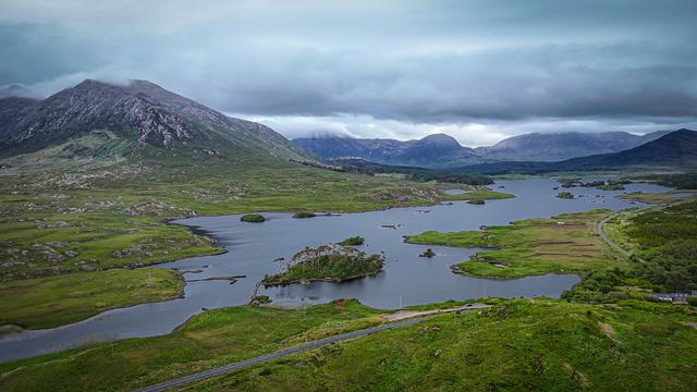 An area landscape view of a series of lake and rivers snaking through green mountains with stormy skies above.