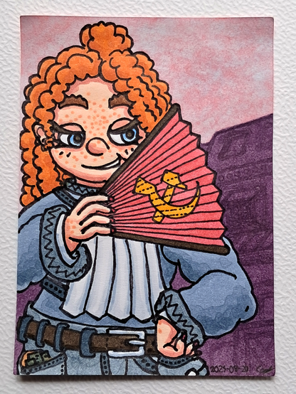 Un portrait de Cynthia, une femme aux cheveux roux frisés et aux yeux bleus, avec un sourire narquois, portant une tenue de travail majoritairement grise, et tenant un éventail rouge avec une faucille et un marteau en jaune par dessus ; en fond des bâtiments dans l'ombre et des cieux roses.