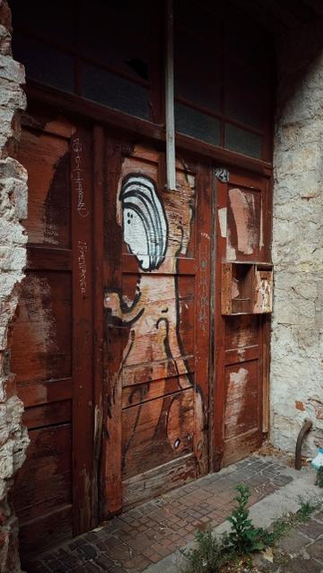 Door of an abandoned house. Streetart, s stylized human being.