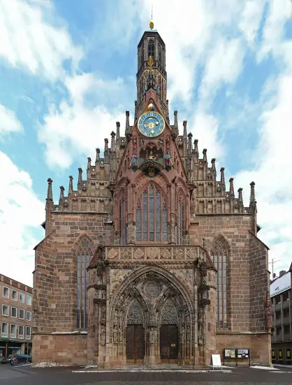 The image shows a large, historical church with a distinctive architectural style. It features elaborate stonework, tall spires, and a prominent clock. The facade is richly detailed, with intricate carvings and sculptures. The sky above is partly cloudy, adding to the dramatic appearance of the structure. This church is likely to be a notable landmark in its location, showcasing Gothic or Romanesque elements typical of such buildings.

Image Credits: Wikimedia / User:Kolossos / CC BY-SA 3.0