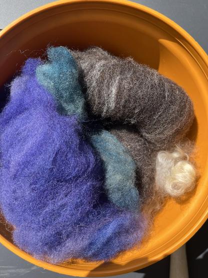 Orange plastic bowl with some brown, teal and purple fleece.