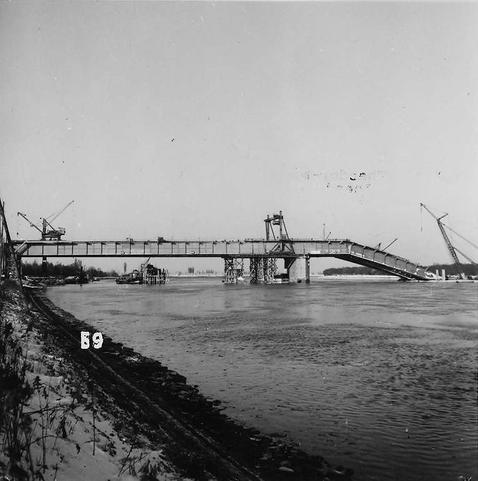 Ansicht von der Seite auf die Brücke. Ein Teil ist abgeknickt und liegt im Rhein.
