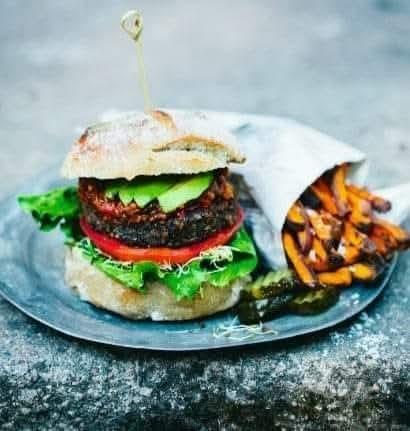 Lentil and mushroom burgers on a bun with avocado & salad served with salted sweet potato fries.
