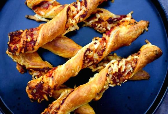 Puff pastry twisted sticks with the filling showing in gaps, laid criss cross on a plate.