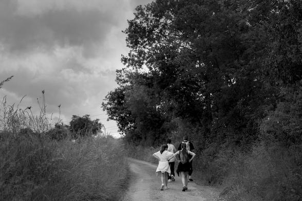 Black and white photography. People walking in a countryside landscape.