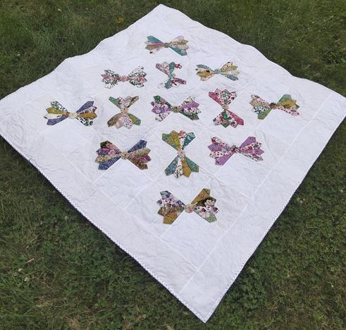 a quilt with multi-colored bow tie designs at different angles, against a light backing , measures 56 x 56 in (142 x 142 cm)