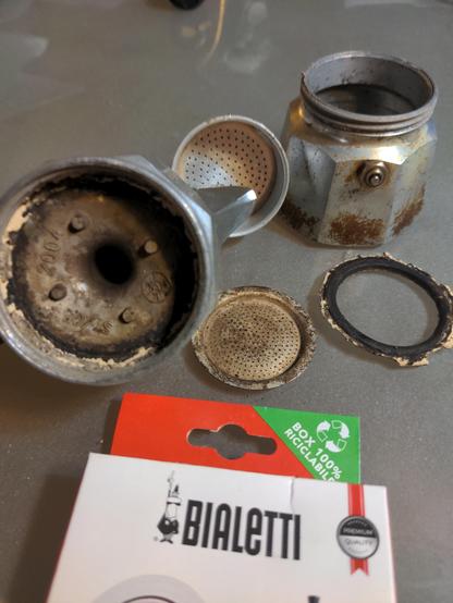 Dirty parts of my Bialetti stove top espresso maker, along with the box of replacement gaskets.