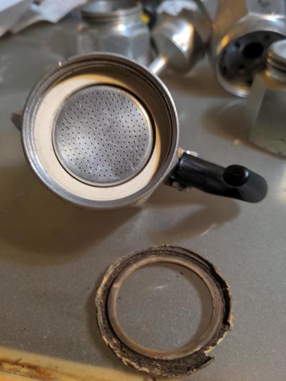 New gasket added to the espresso maker.  It is white in colour rather than coffee stained dirty, as the older gasket was.  Older gasket lying in front for comparison.