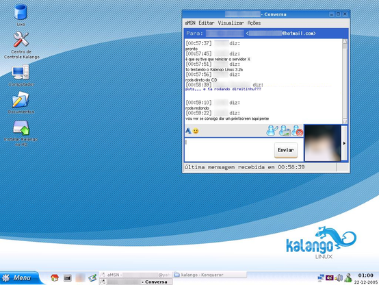 Desktop (KDE 3) screenshot of Brazilian GNU/Linux distribution Kalango, version 3.2a. Its colors are mainly blue, the wallpaper having a lower right "kalango linux" logo depicting a lizard. There are icons left with text from Portuguese: Trash bin, Kalango Control Center, Computer, Documents, Install Kalango on HD. The lower task bar has K Menu, icons for Home, Terminal, Web (blurred), Show Desktop, the open windows list/buttons, system tray having icons for network, input language (en), sound, aMSN, time/date (1 a.m., December 12, 2005. There is also an aMSN chat window open, having a (blurred) contact picture, some control elements and this text, from Portuguese:

[00:57:37] (one blurred name) says: done
[00:57:45] I had to restart the X server
[00:57:51] I'm trying Kalango Linux 3.2a
[00:57:56] it runs directly from the CD
[00:58:39] (another longer blurred name) says: wow... and is it running all right?
[00:59:10] (the first) says: it runs smoothly
[00:59:22] I'll try to take a screenshot here, wait