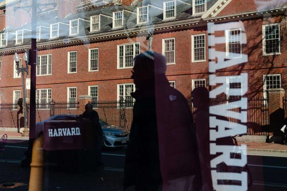 Harvard University is reflected in the window of a merchandise store across the street from the school on April 17, 2025, in Cambridge, Massachusetts.
