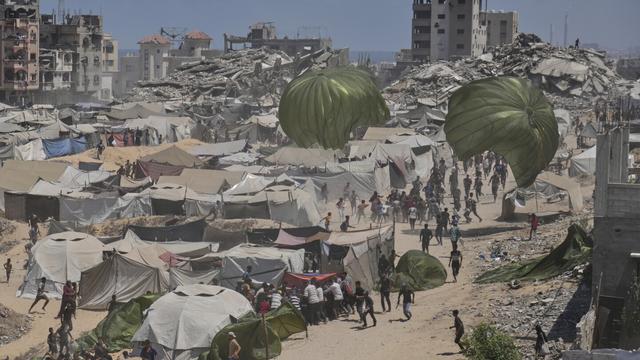 Palestinians rush to collect humanitarian aid airdropped by parachutes into Gaza City, northern Gaza Strip, Thursday, Aug. 7, 2025. (AP Photo/Jehad Alshrafi)