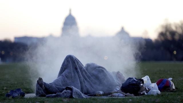 The U.S. Capitol building gives backdrop to a homeless man resting on a steam vent on the National Mall, Dec. 18, 2019, on Capitol Hill in Washington. (AP Photo/Julio Cortez, File)