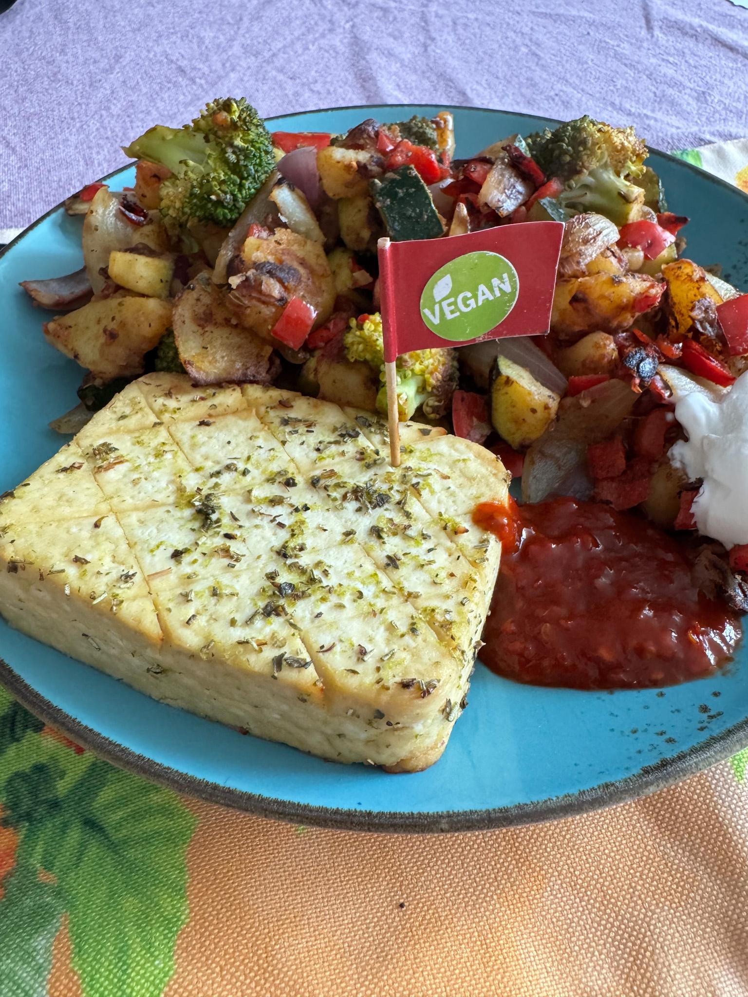 Vorne ein Block Tofu mit veganfahne, dahinter Gemüse