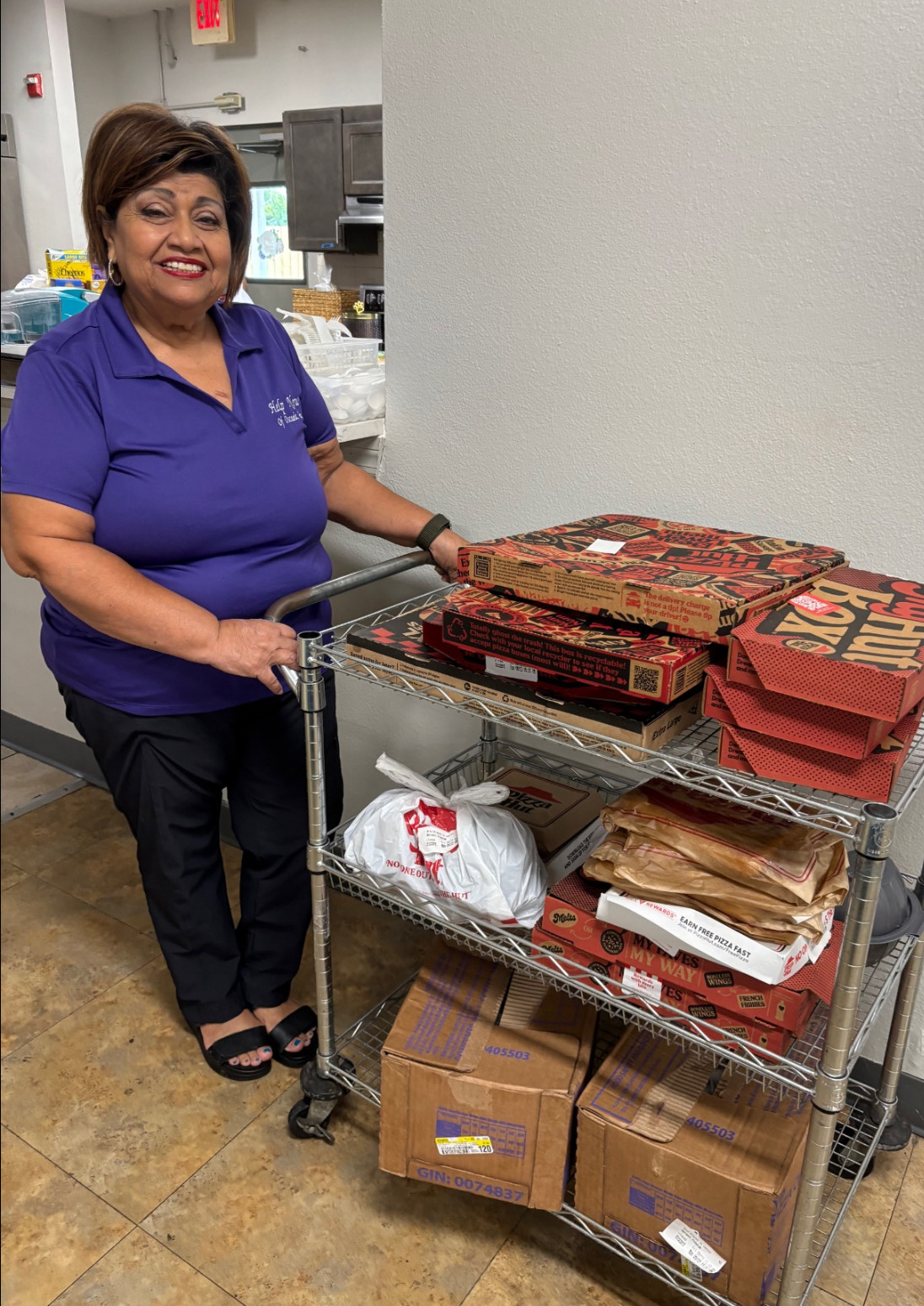 A Help Now Shelter volunteer stands beside food donated by Relief Alliance, Providence Ministries, JFC, and Pizza Hut St. Cloud to support local families and fight hunger.