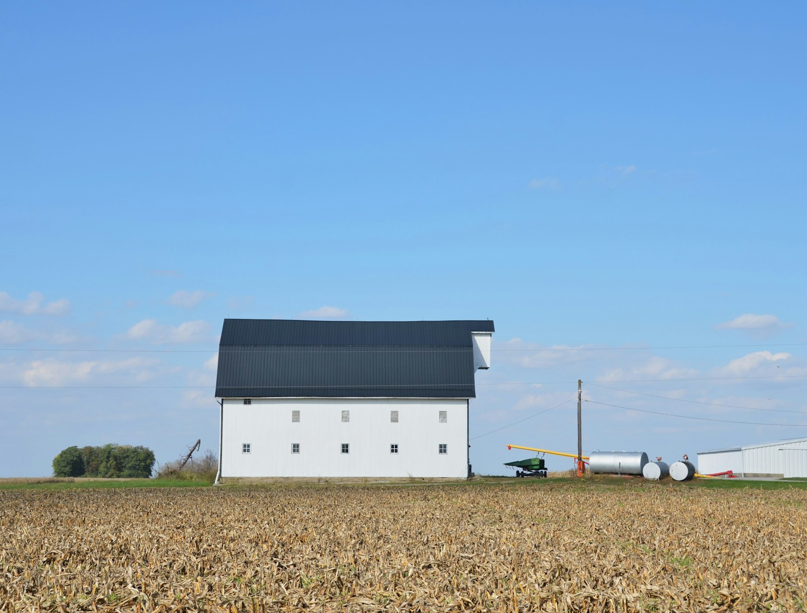 White barn with dark roof in a field.